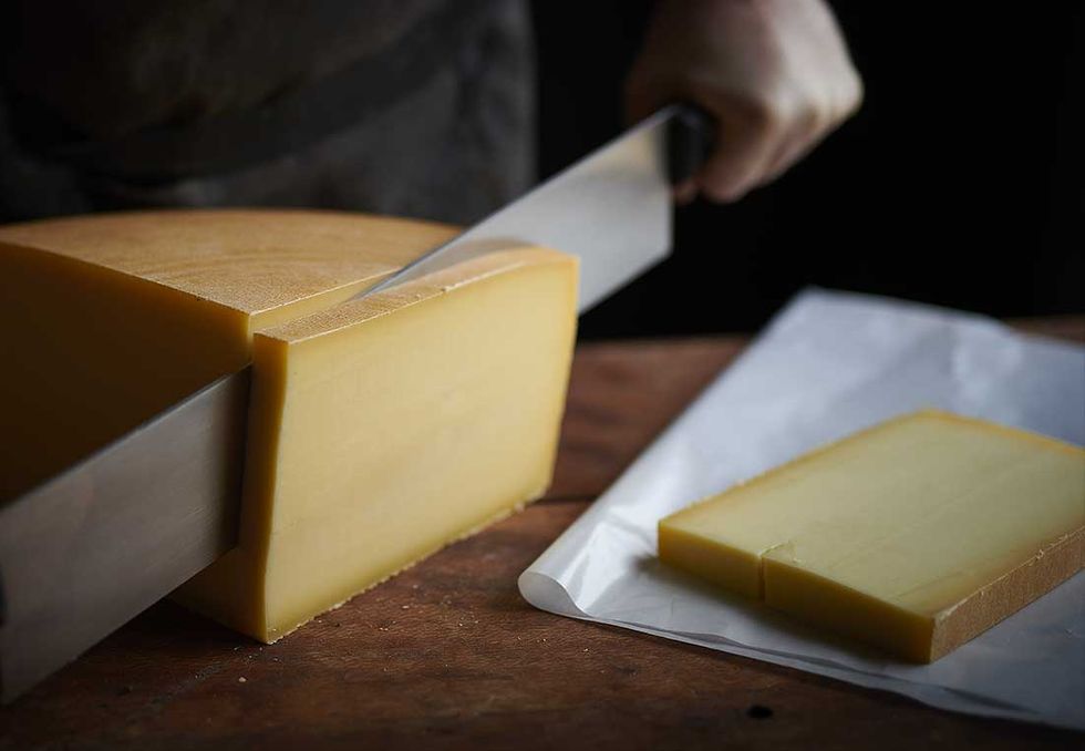 Un morceau de fromage de la meule du plateau en train d'être découpé